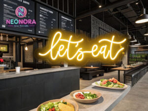 "Let's Eat" custom LED neon sign glowing in warm white light, mounted above a modern dining table with plates and wine glasses.