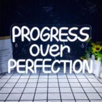 "Progress Over Perfection neon sign featuring a motivational quote in soft LED light, USB-powered with dimmable function, ideal for classroom, mental health office, man cave, home or workplace wall decor."