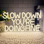 "Slow Down You Are Doing Fine neon sign featuring a calming cursive design, USB-powered dimmable LED light for inspirational wall decor, ideal for bedroom, classroom, office, party, or motivational gift decor (15.7 x 8.2 in)."